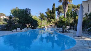 A swimming pool surrounded by rocks and tropical plants. - Beautiful Studio in a large Provencal Villa - Swimming pool (Sausset-Les-Pins)