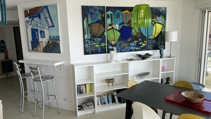 Een moderne eetruimte met een zwarte tafel, witte stoelen en een boekenplank vol boeken.