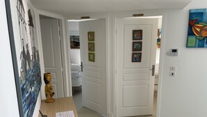 Een gang met een houten bureau, een sculptuur en een deur naar een slaapkamer.