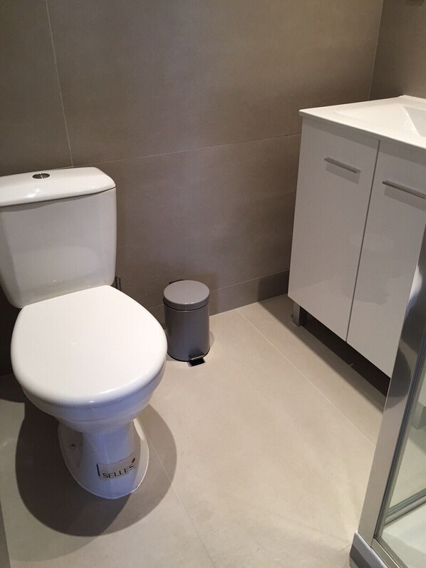 A bathroom with a toilet, a trash bin, and a cabinet. - Apartment in renovated pool villa 2025 (Porto-Vecchio)