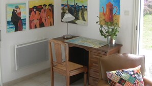 A dining area with a wooden table, chairs, and a map. There are paintings on the wall and a potted plant on the table. - MODERN HOUSE CROZON MORGAT (Crozon)