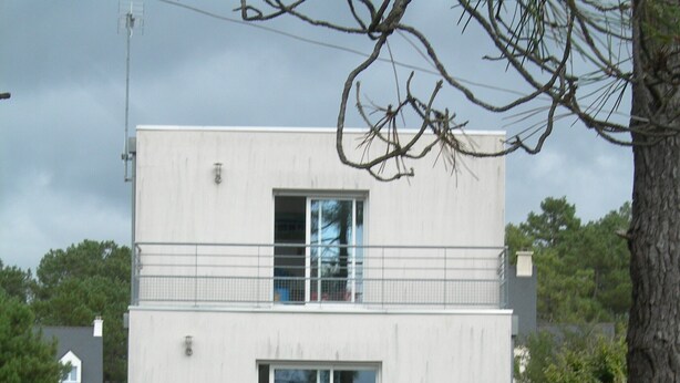 A modern two-story building with a flat roof, large windows, and a small patio area with outdoor furniture. - MODERN HOUSE CROZON MORGAT (Crozon)