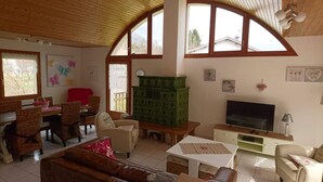 Un salon confortable avec un téléviseur, des meubles en osier et une grande fenêtre.