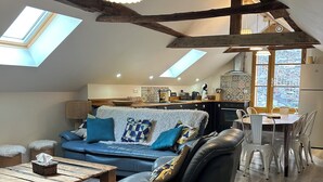A loft-style living room with a sofa, a coffee table, and a dining area with chairs. - Spacious barn, comfortable for family stay. Charming place, outdoor terrace (Bagnères-de-Luchon)