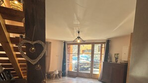 A spacious living area with a wooden staircase, a heart-shaped decoration, a ceiling light, and a view through glass doors. - Spacious barn, comfortable for family stay. Charming place, outdoor terrace (Bagnères-de-Luchon)