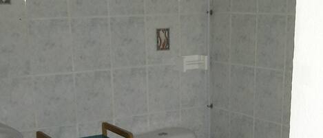 Une petite salle de bain comprenant des toilettes, un lave-linge et une chaise en bois avec un siège vert.