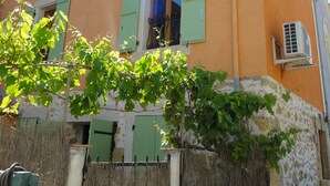 Ein zweistöckiges Gebäude mit steinernen Fundament, orangefarbenen Wänden und grünen Fensterläden.