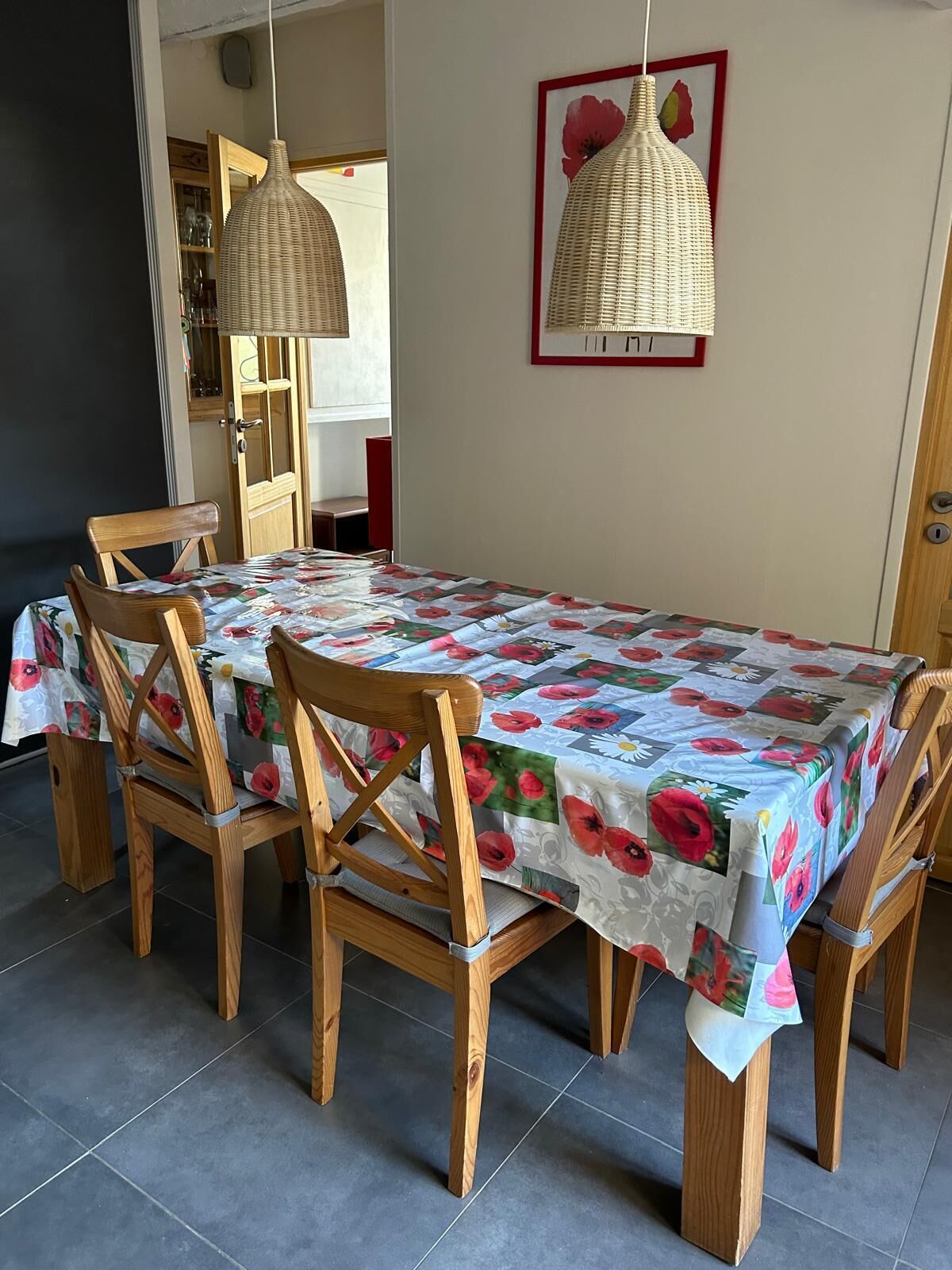 Un coin repas avec une table recouverte d’une nappe à motifs floraux, entourée de chaises en bois.