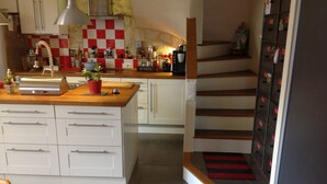 Eine moderne Küche mit weißen Schränken, einer Holz Arbeitsplatte und einer roten und weißen Schachbrett-Spritzschutzwand.