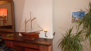 Un barco modelo sobre una repisa, una vela encendida, un espejo y un cuadro enmarcado en la pared.