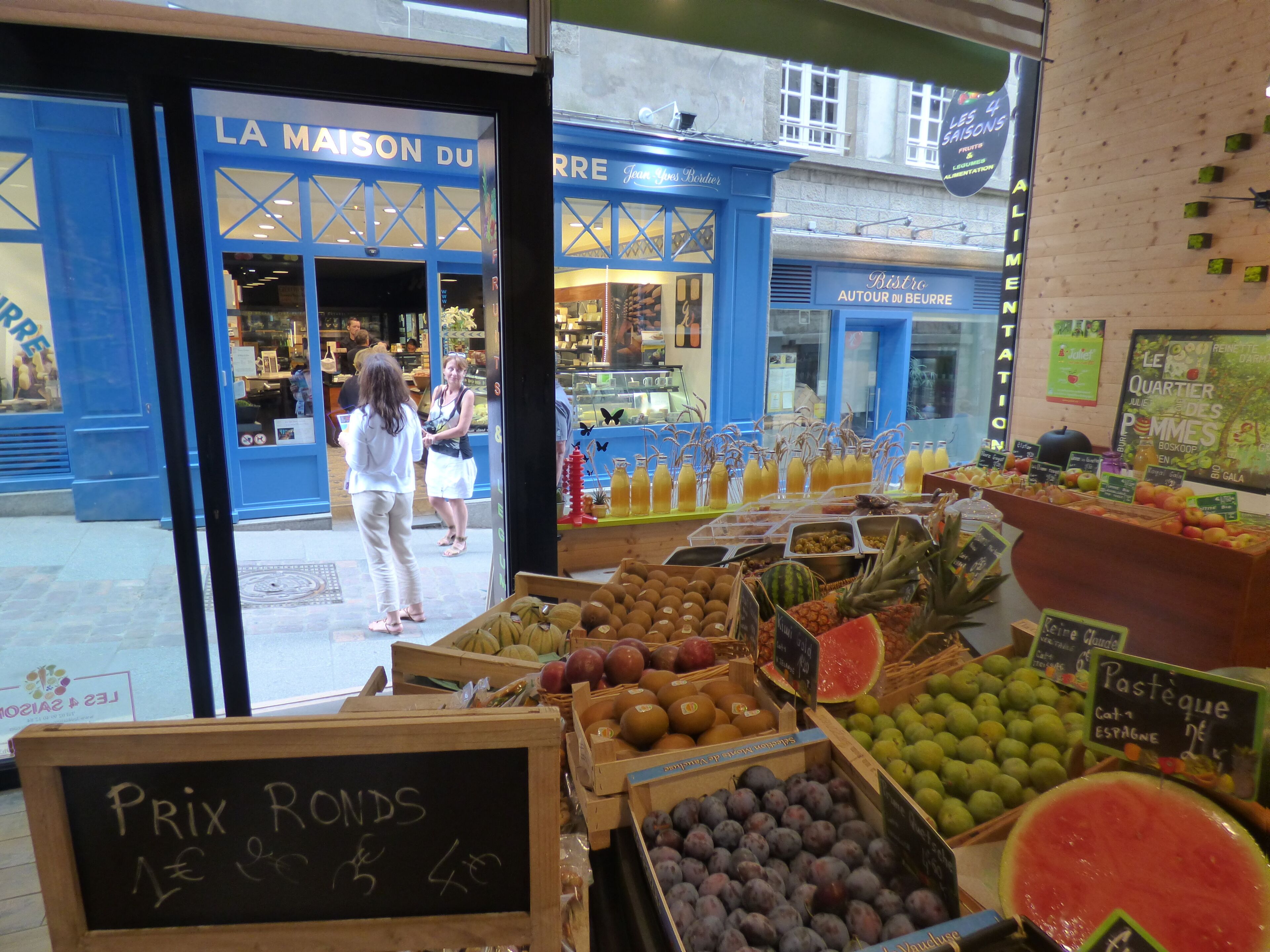 Een kraampje met verschillende soorten fruit en een schoolbord waarop de prijzen staan.
