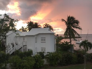 A white building with a staircase and a view of the sea at sunset.
