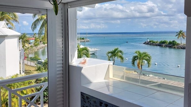A balcony with a view of the ocean and palm trees.