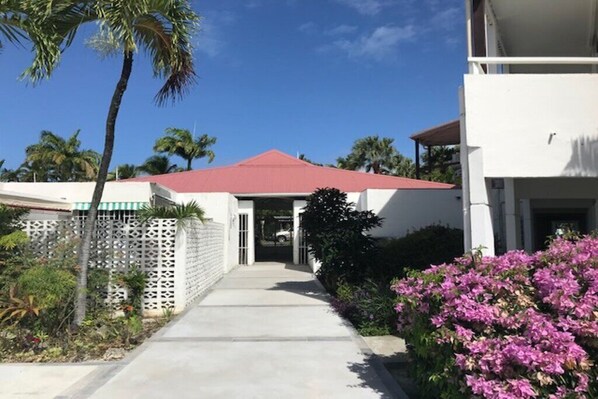 A building with a red roof, a white exterior, and a concrete pathway leading to the entrance.
