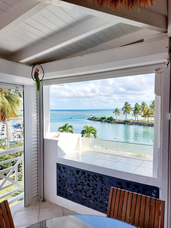 A balcony with a view of the ocean, palm trees, and a small island.