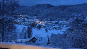En snötäckt by i skymningen, med hus och en kyrka som lyser upp i fjärran.
