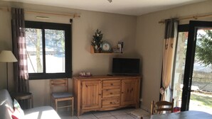 Ein Zimmer mit einem Holzkasten, einem Fernseher, einem Sessel und einem Tisch.
