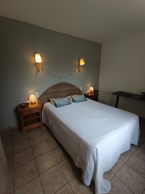 Une chambre Ă coucher comprenant un lit, deux tables de chevet, des lampes fixĂ©es au mur et une petite table dâappoint.