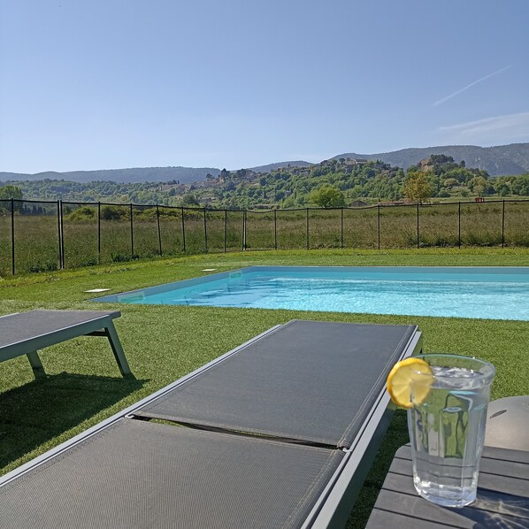 Una piscina con vistas a un paisaje rural, que incluye colinas y un pueblo.