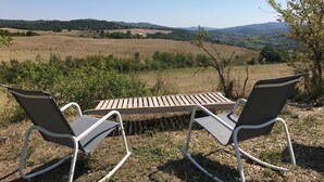 A table and two chairs in an outdoor setting with a view of a hilly landscape. - PROMOTION summer: from 13/07 to 20/07 and 17/08 to 24/08 945 euros instead of 1500 eur (Verzeille)