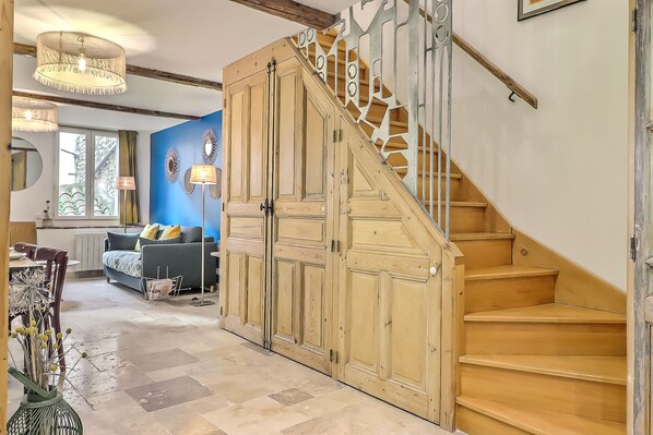 A staircase with wooden steps and a metal railing, leading to a landing with a blue wall and decorative mirrors.