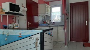 A kitchen with white cabinets, a microwave, and a window with a view. - Newly built house, all mod cons (La Turballe)