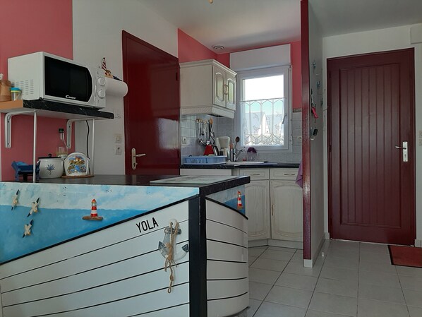 A kitchen with white cabinets, a microwave, and a window with a view. - Newly built house, all mod cons (La Turballe)