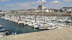 A marina with numerous boats docked, stone piers, and buildings in the background. - Newly built house, all mod cons (La Turballe)