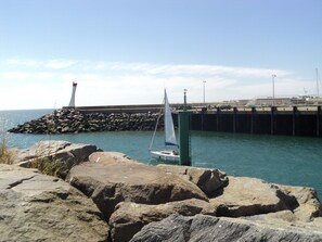 A rocky shoreline with a lighthouse and a pier extending into the water.