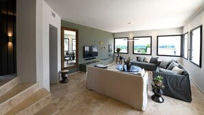 A modern living room with a sofa, TV, and large windows. - Les Loges en Provence - Villa "360 (Villeneuve-lès-Avignon)
