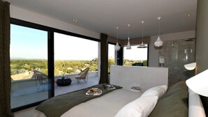 A modern bedroom with a large bed, a balcony with a view, and a shower area. - Les Loges en Provence - Villa "360 (Villeneuve-lès-Avignon)