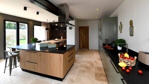 A modern kitchen with a central island, built-in appliances, and a view to the outdoors. - Les Loges en Provence - Villa "360 (Villeneuve-lès-Avignon)