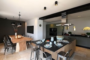 Eine moderne Küche mit Kochinsel, eingebauten Geräten und einem Essbereich mit Holztisch und Stühlen.
