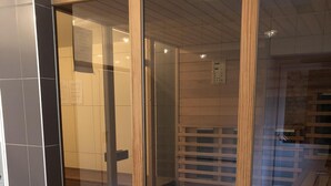 Un interior moderno con un divisor corredizo de vidrio que da a una habitación con piso de madera y estantes empotrados.