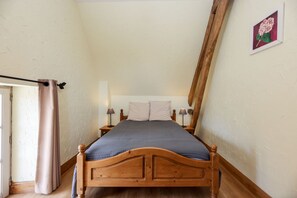 A bedroom with a wooden bed, two bedside lamps, a window with curtains, and a wall-mounted picture. - Gîte with covered swimming pool on the Opal Coast (Tingry)