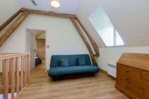 Un dormitorio tipo loft con una escalera de madera, un sofá, un aparador y un tragaluz.