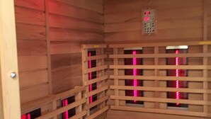 Una sauna con paredes y bancos de madera, equipada con paneles de luz roja.