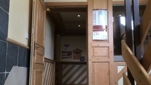 Eine Holztreppe führt zu einem Raum mit gefliestem Boden und einem an der Wand befestigten Schild.