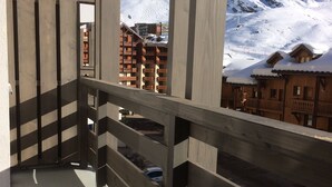 Ein Balkon mit Blick auf schneebedeckte Berge und Gebäude.