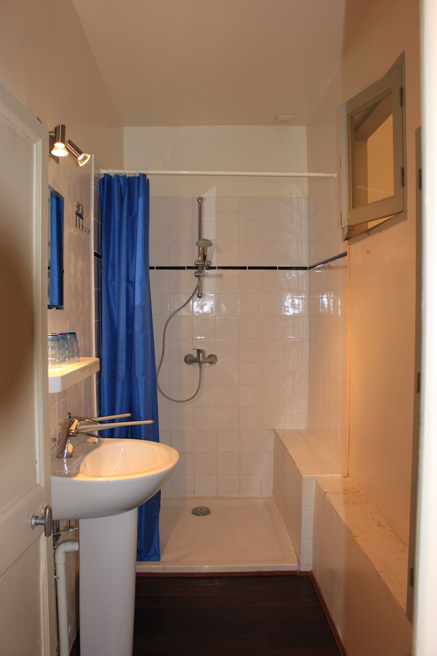 A small bathroom with a white sink, a shower with a blue curtain, and a mirror on the wall.