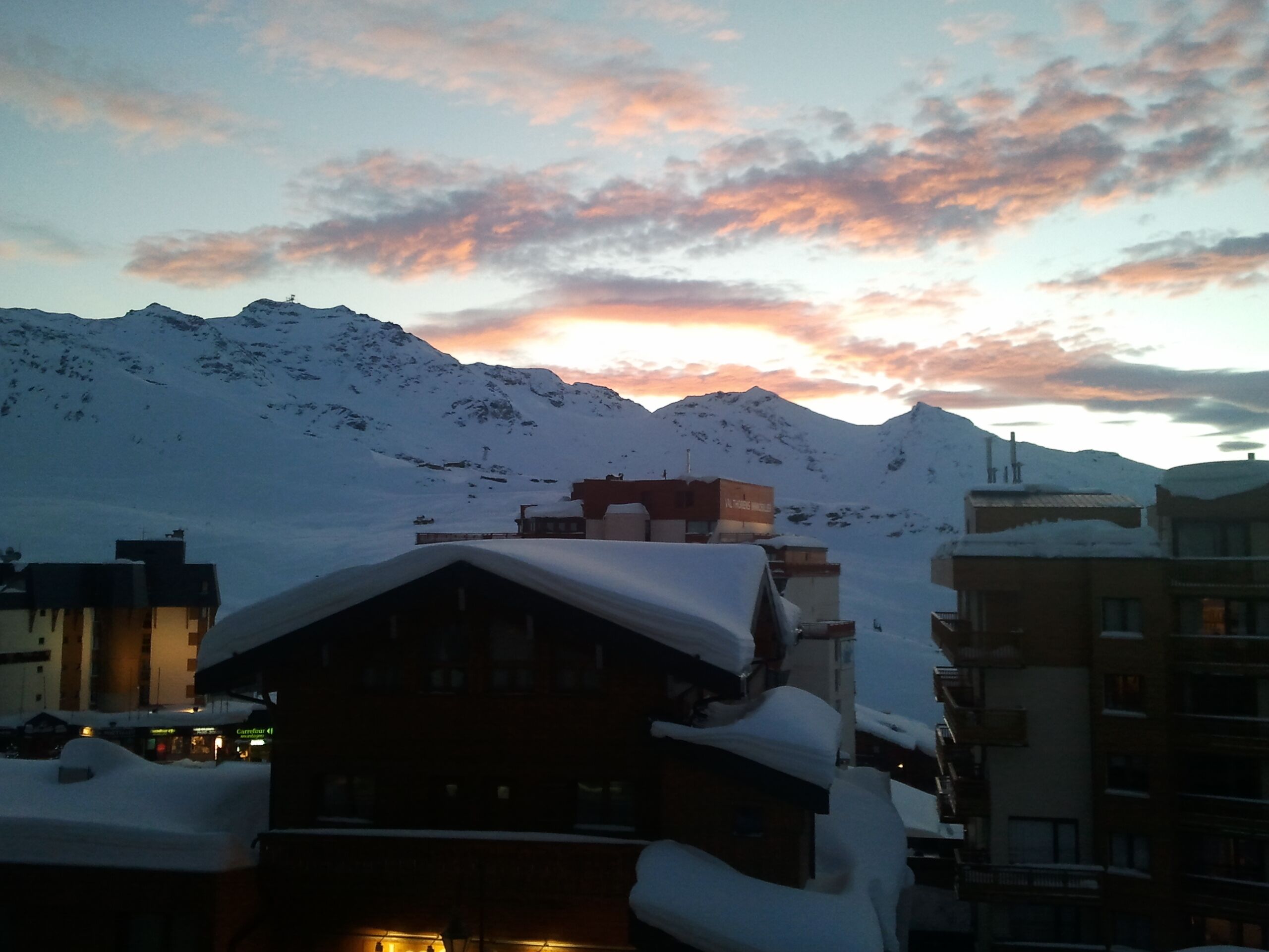 A snow-covered mountain landscape with a building featuring a sloped roof and a visible sign.