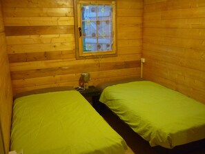 A small, wooden cabin room with two beds and a window. - WOODEN CHALET RENTAL IN THE HEART OF NATURE (Neschers)