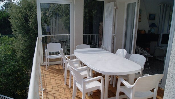 A balcony with a white table and chairs, a glass door, and a view of greenery. - NEO-PROVENCAL VILLA WITH SECURE INFINITY POOL (Roquebrune-Sur-Argens)