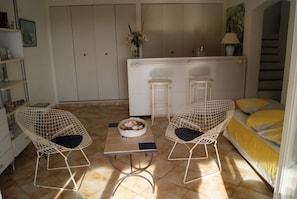 A small, cozy room with two wicker chairs, a small table, and a bed with yellow bedding. There is a white cabinet with a mirror and a vase with flowers on top. - NEO-PROVENCAL VILLA WITH SECURE INFINITY POOL (Roquebrune-Sur-Argens)