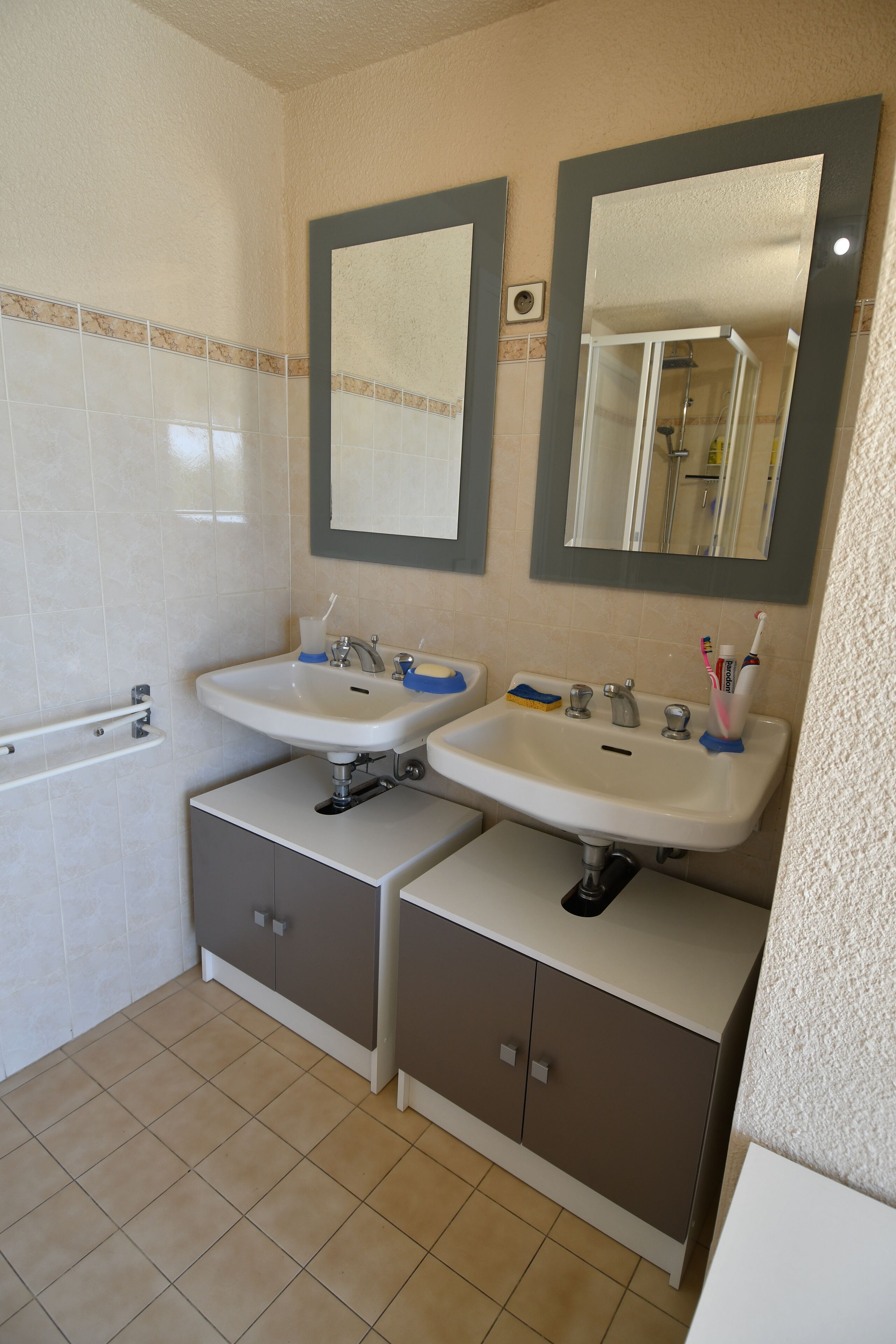 A bathroom with two sinks, a bathtub, and a shower. There are cabinets below the sinks and a towel rack on the wall.