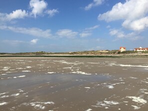 Una playa con arena y algunos edificios al fondo.