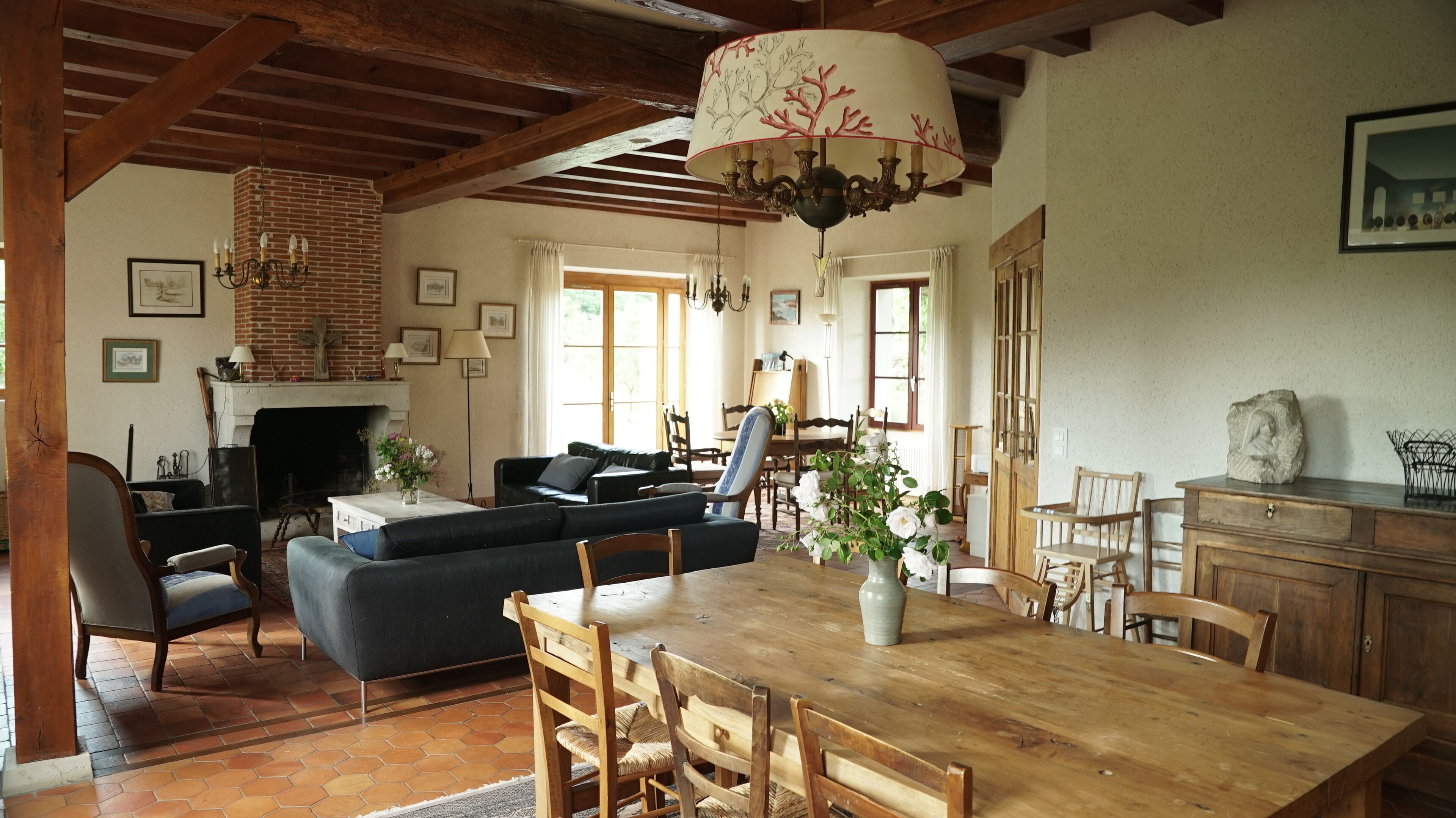 A spacious living room with a fireplace, a dining area with a wooden table and chairs, and a cozy seating area with a sofa and armchairs.