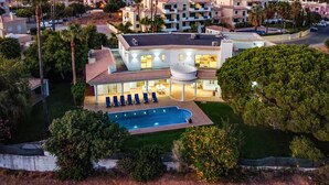 Una casa grande de varios pisos con piscina, varios balcones y un jardín bien cuidado.