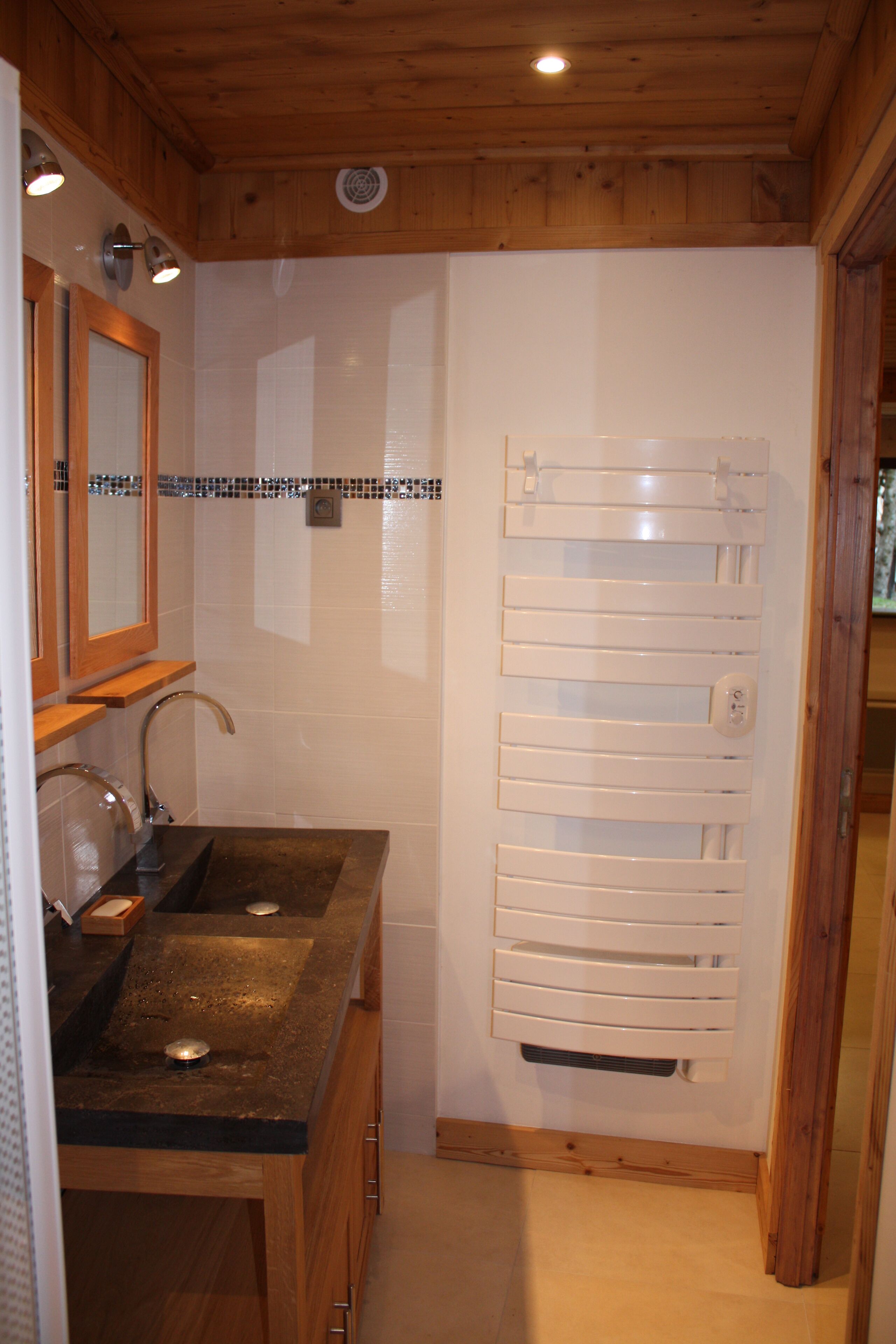 A bathroom with a wooden vanity, a mirror, and a towel rack.