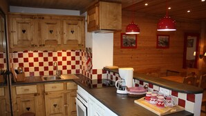 Een keuken met houten kastjes, een zwart-wit betegelde achterwand, een spoelbak, een koffiezetapparaat en een wasmachine.